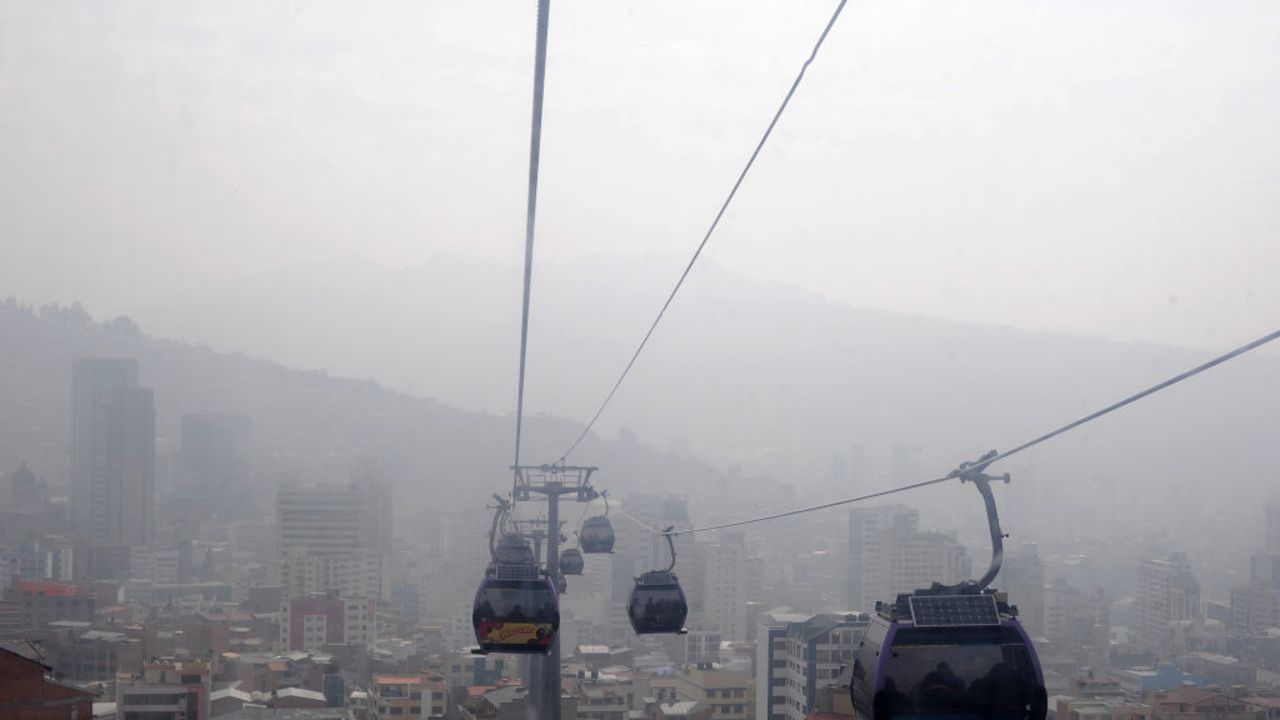 Cable car cabins descend from El Alto to La Paz, mostly covered by smoke from forest fires in eastern Bolivia, on September 9, 2024. (Photo by JORGE BERNAL / AFP) (Photo by JORGE BERNAL/AFP via Getty Images)