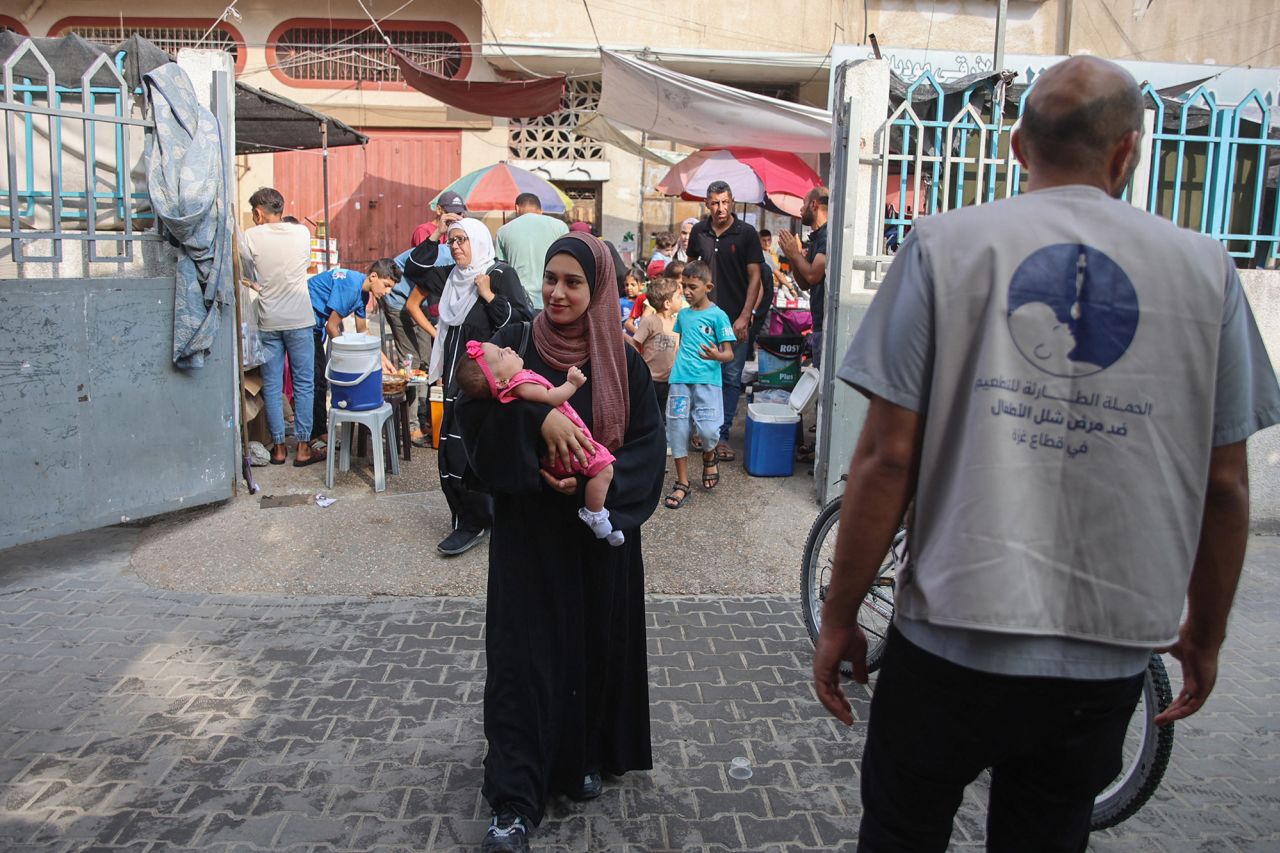 Palestinians leave with their children after vaccination during an inoculation drive at the al-Daraj neighborhood clinic in Gaza City on September 10.