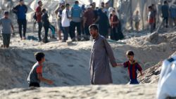 A Palestinian man holds the hand of a child as he and others inspect the damage at the site of Israeli strikes on a makeshift displacement camp in Mawasi Khan Yunis in the Gaza Strip on September 10, 2024, amid the ongoing war between Israel and Palestinian militant group Hamas. Gaza's civil defence agency said that an Israeli strike on a humanitarian zone in the south of the Palestinian territory killed 40 people and wounded 60 others, with the Israeli army saying it had targeted a Hamas command centre in the area. (Photo by Bashar TALEB / AFP) (Photo by BASHAR TALEB/AFP via Getty Images)