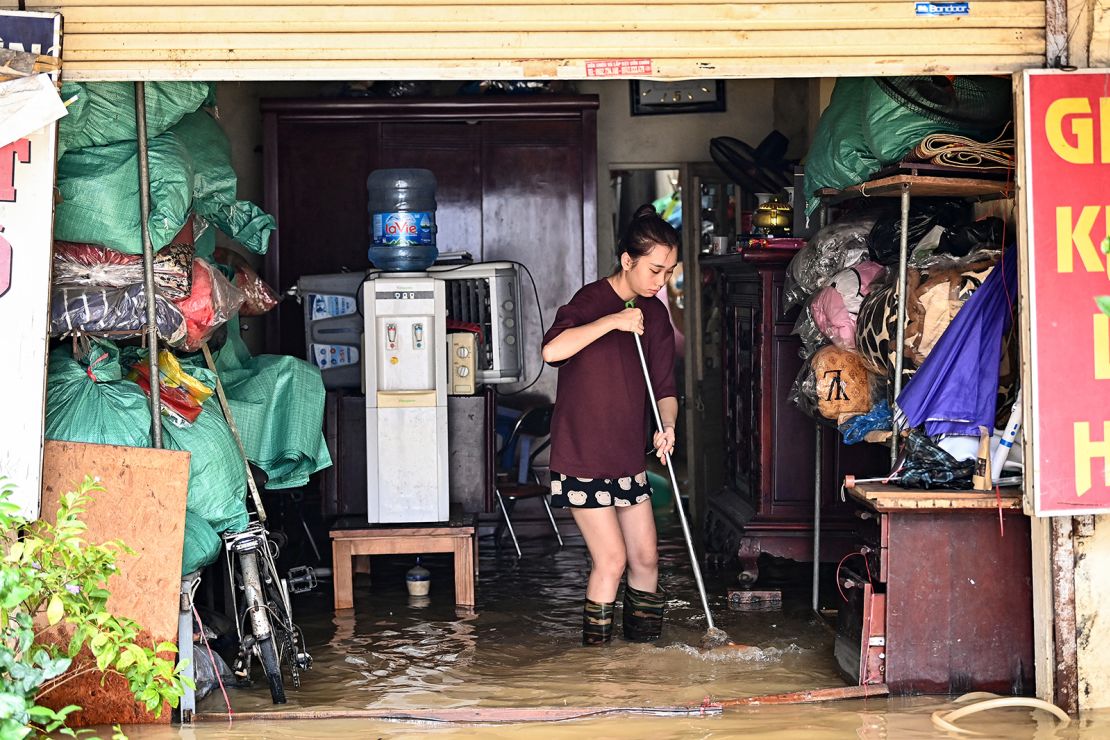 A woman sweeps flood waters outside her home in Hanoi, Vietnam on September 12, 2024.