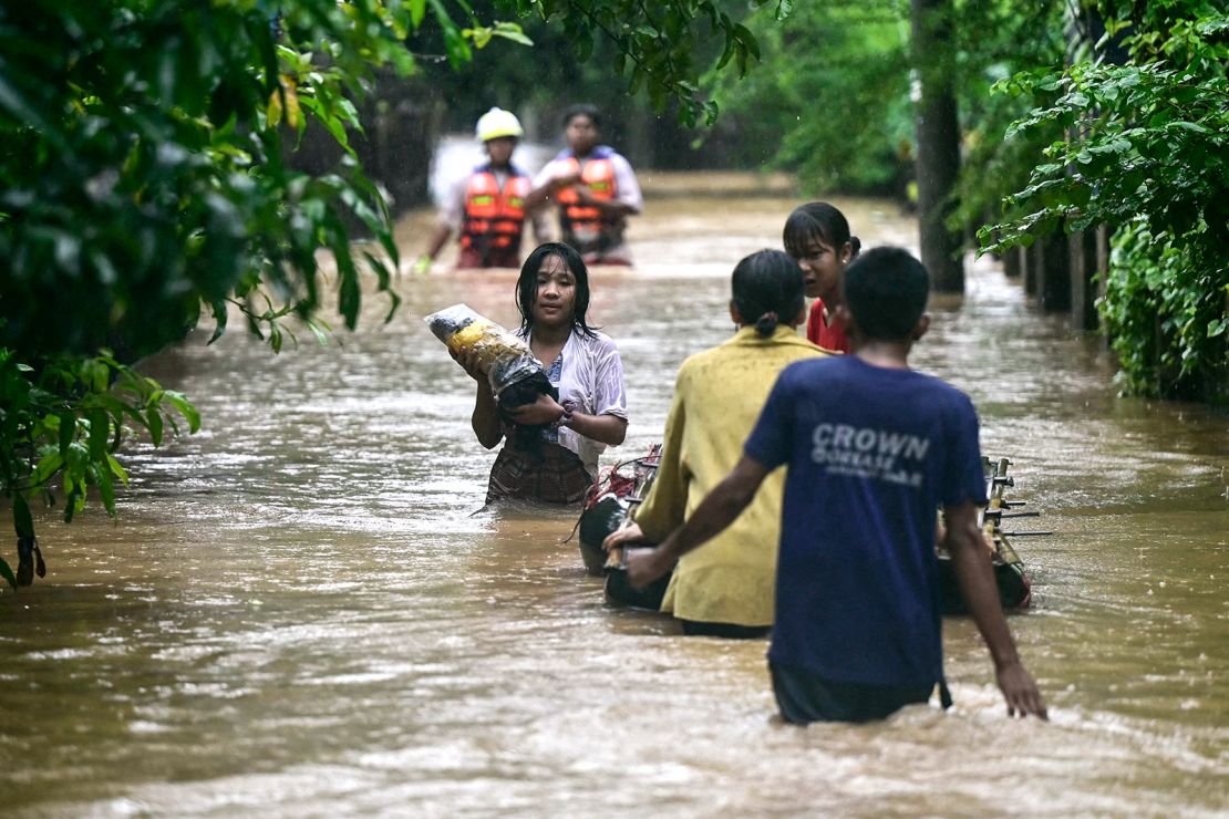 Villagers wade through waist-deep floodwaters in Taungoo in Myanmar's Bago region on September 12, 2024.