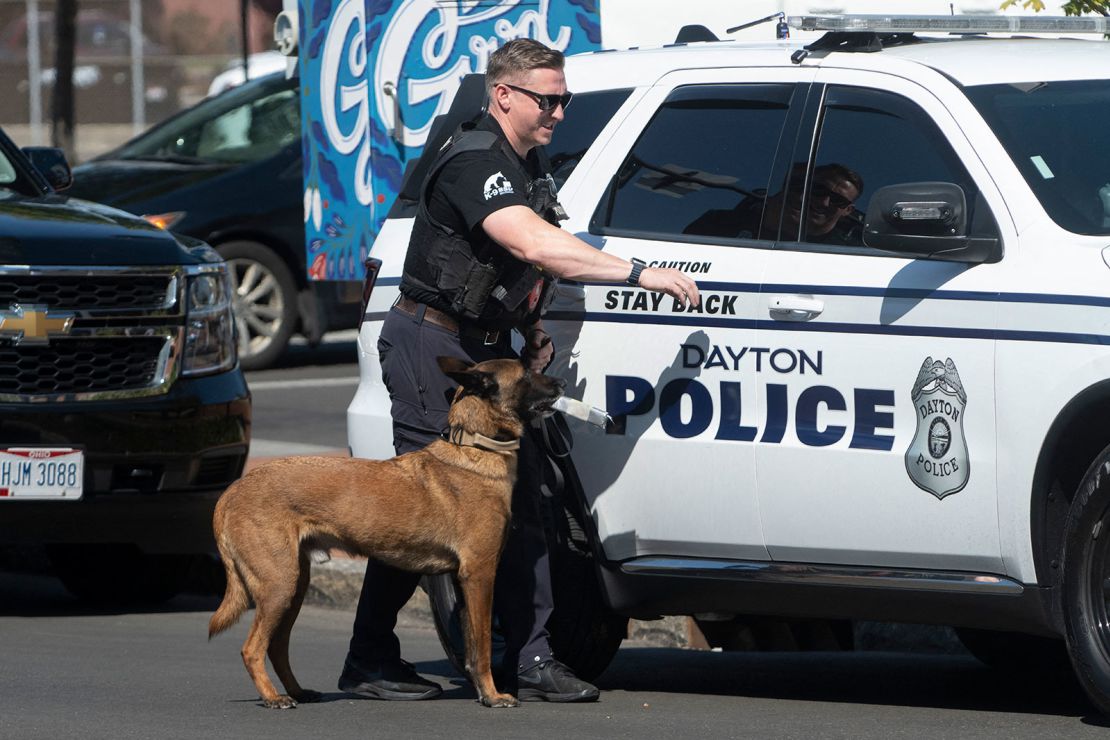 A police officer and his dog return to their car after searching the grounds of Springfield City Hall for explosives following a bomb threat against the building earlier that day, September 12, 2024, in Springfield, Ohio.