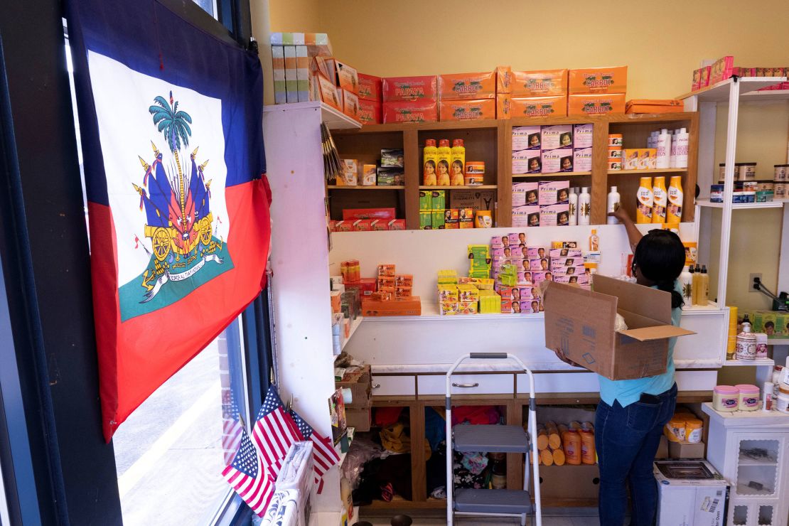 Creations Market shop owner Philomene Philostin, a naturalized US citizen of Haitian origin, shelves merchandise in her store that caters mainly to Haitian residents in Springfield, Ohio.