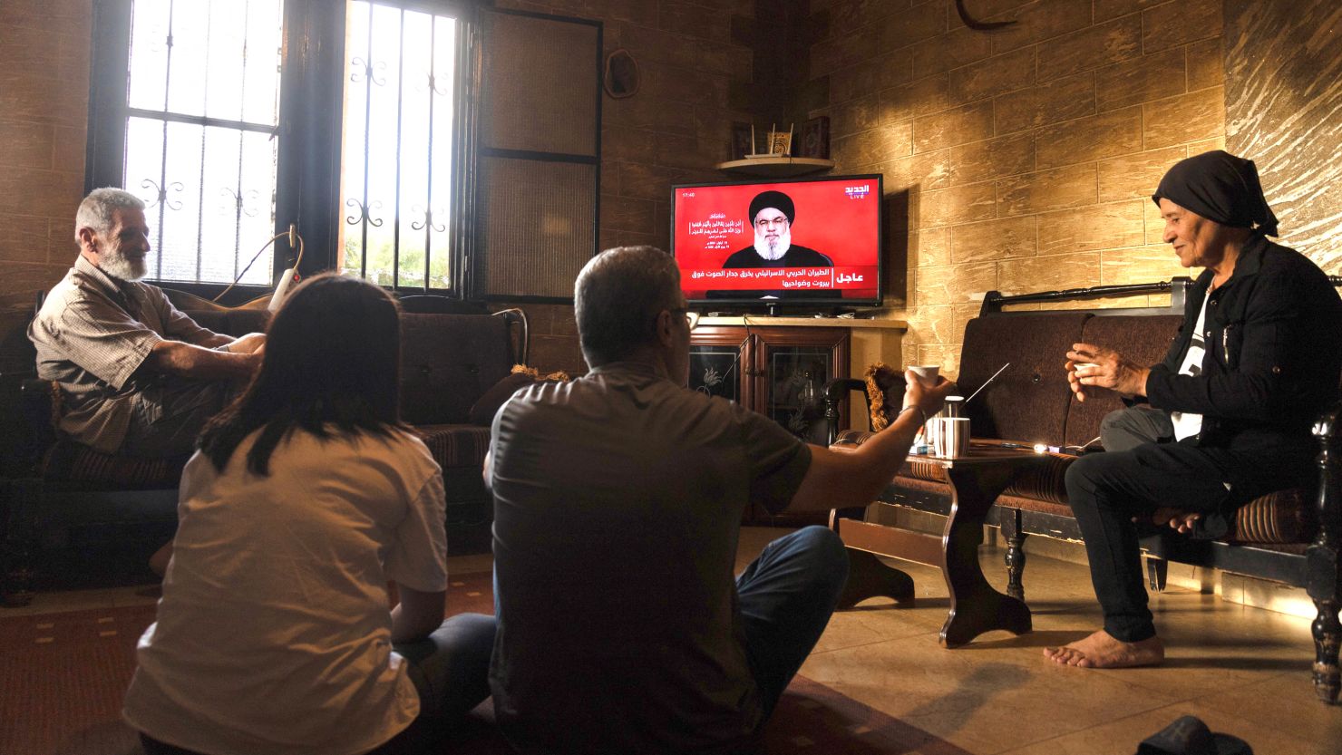 People watch a televised speech by the leader of the Hezbollah movement Hassan Nasrallah inside a house in the southern Lebanese village of Zawatar on September 19.