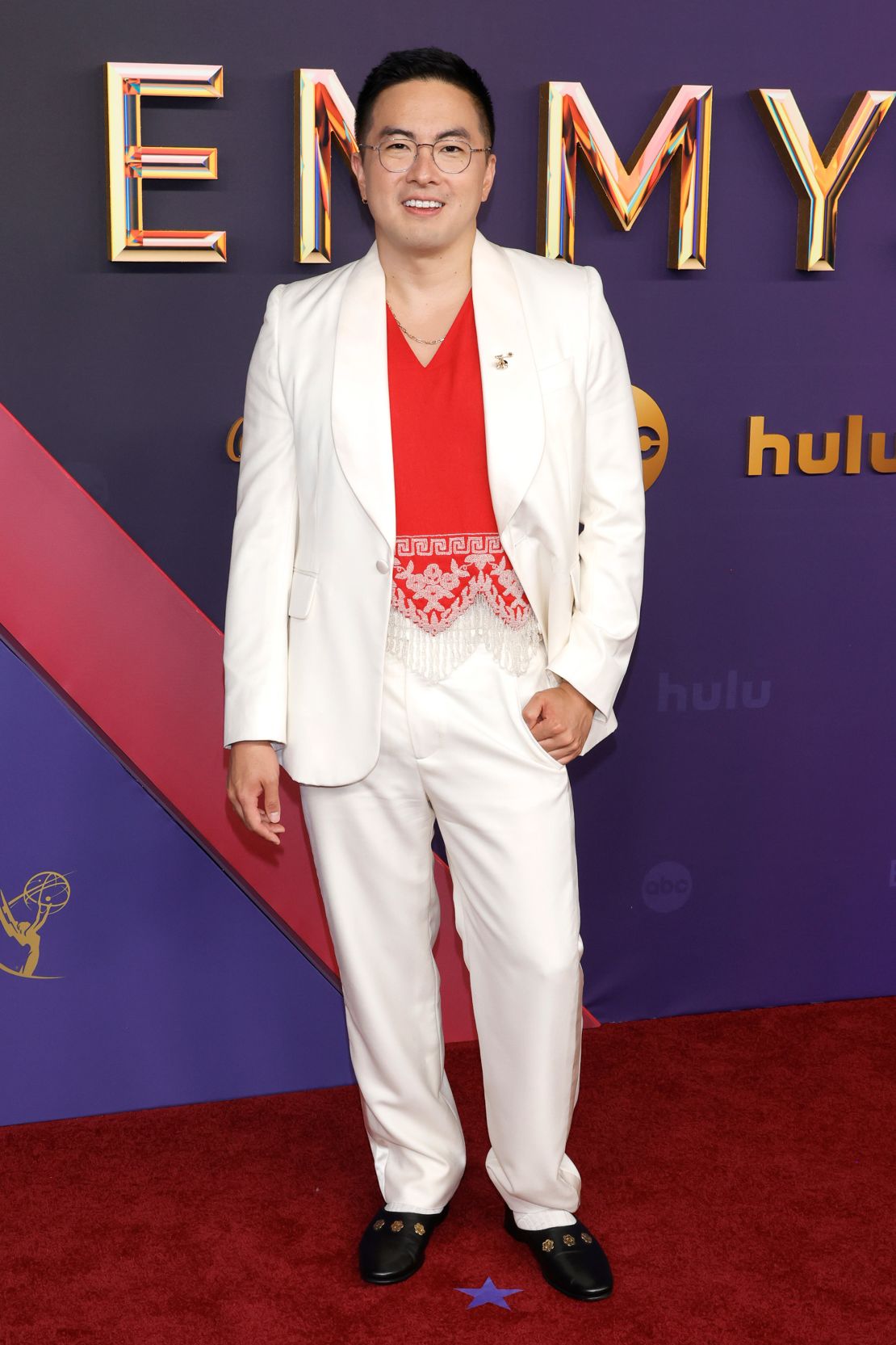 Bowen Yang, nominated as Outstanding Supporting Actor for “Saturday Night Live,” wore a cream Bode suit jacket over a bright red tasseled top. He accessorized with jewelry, a lapel pin and a watch (not pictured) — all by Cartier.