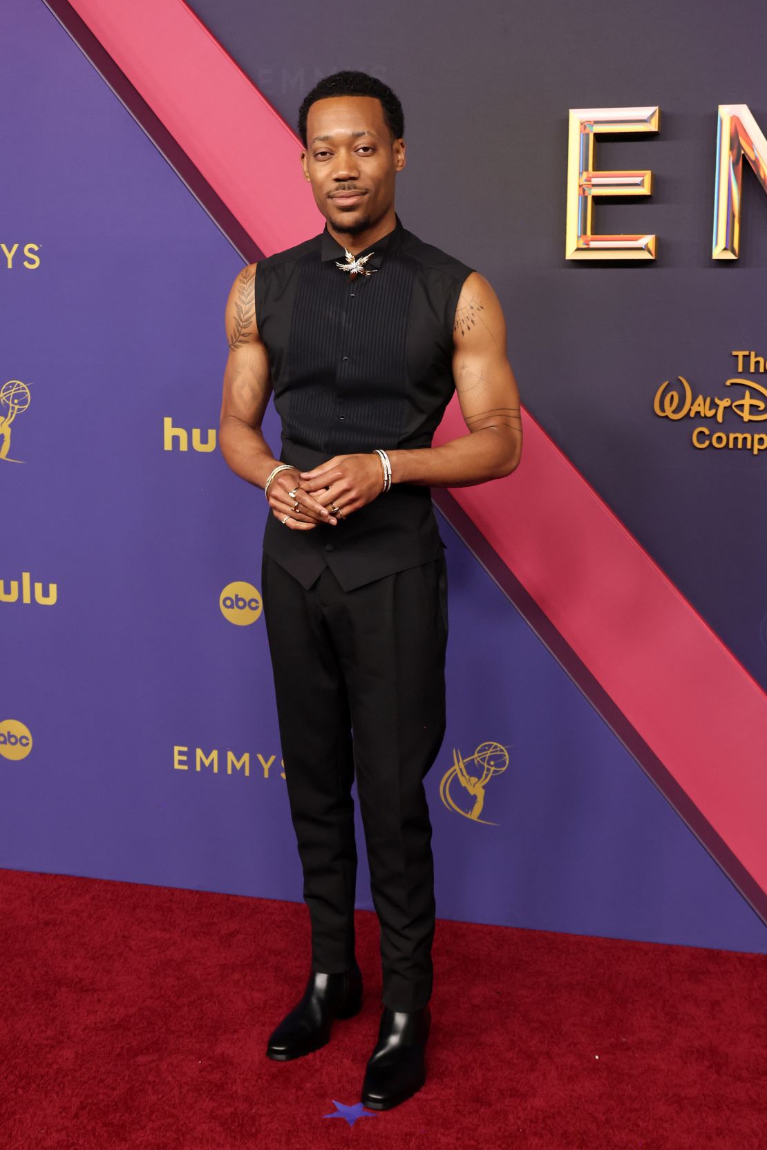 Tyler James Williams paired wool trousers with a sleeveless martini-fit Dolce & Gabbana tuxedo shirt and a pair of leather boots.