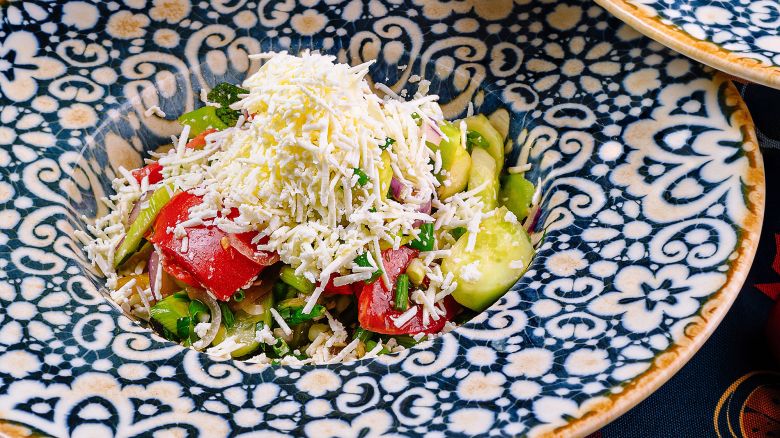 Plates with shopska salad, a traditional bulgarian salad with cucumbers, tomatoes, peppers, onions and sirene, served on a table