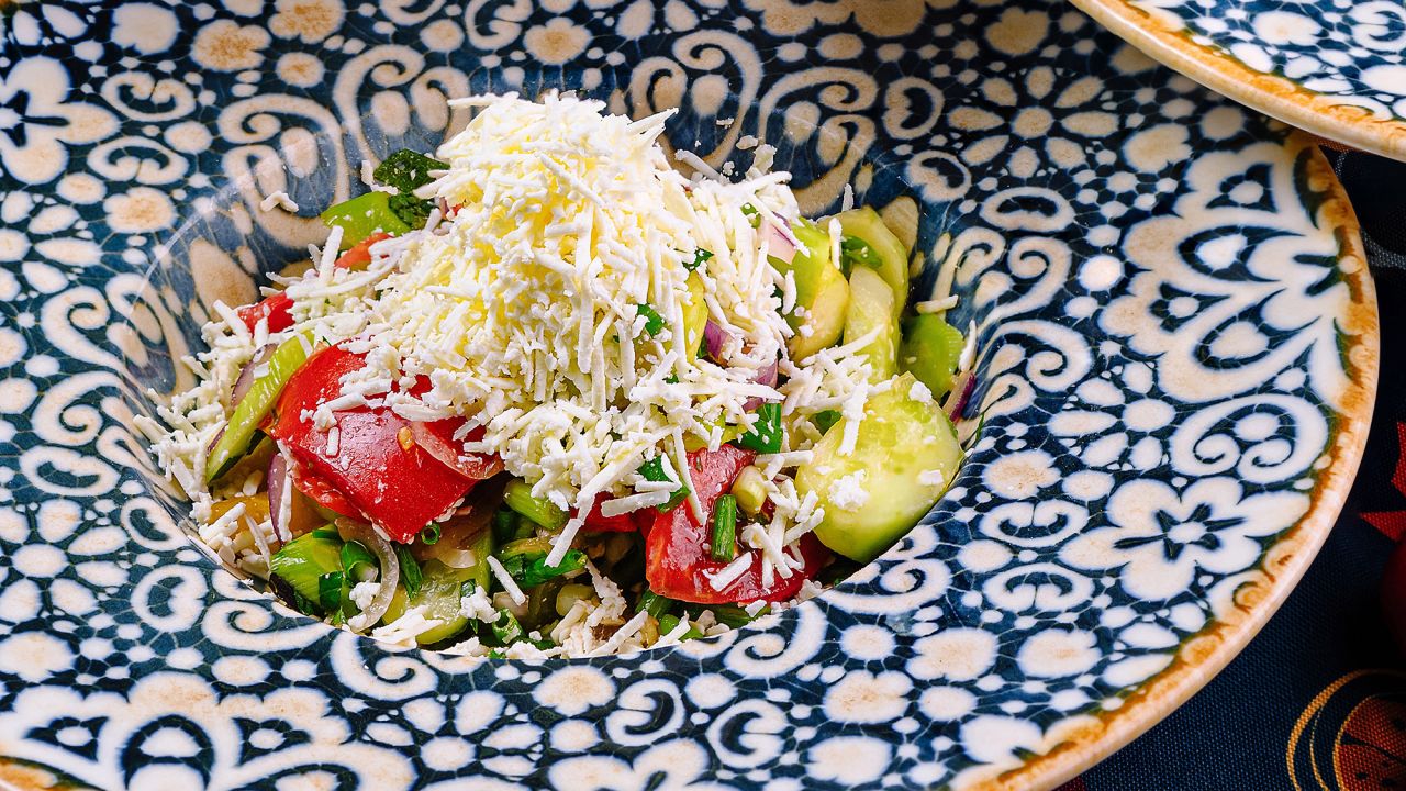 Plates with shopska salad, a traditional bulgarian salad with cucumbers, tomatoes, peppers, onions and sirene, served on a table
