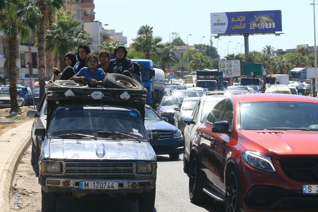 A Syrian family sit with their belongings in the back of a truck as they wait in a traffic jam in the southern Lebanese city of Sidon on September 23, 2024.