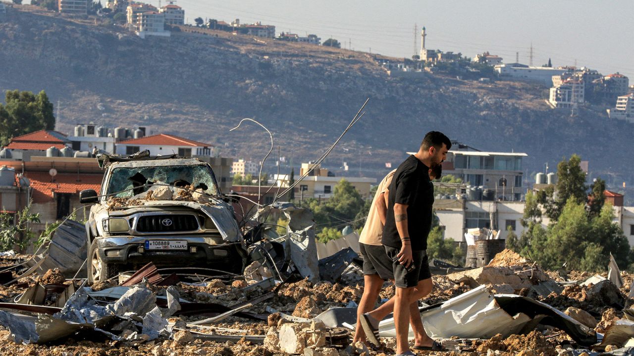 People inspect the site of an Israeli air strike in Jiyeh along the highway linking Beirut to the southern city of Sidon on September 25, 2024.