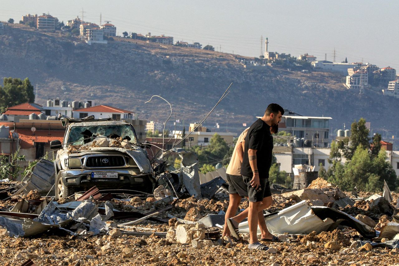 People inspect the site of an Israeli air strike in Jiyeh along the highway linking Beirut to the southern city of Sidon on September 25, 2024.