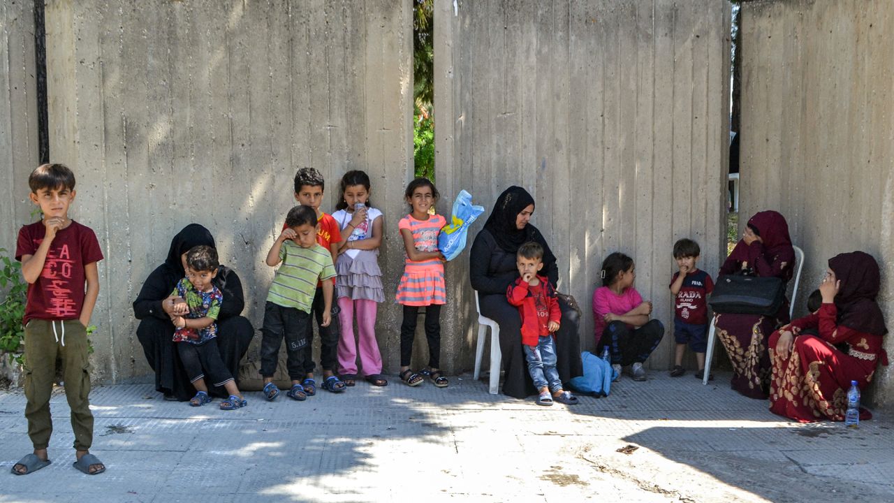 People displaced by conflict from southern Lebanon wait outside a temporary reception shelter in the northern city of Tripoli on September 25.