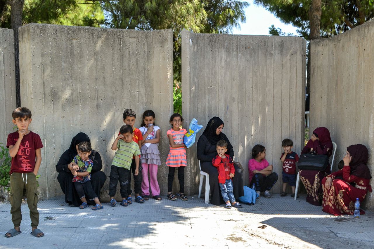 People displaced by conflict from southern Lebanon wait outside a temporary reception shelter in the northern city of Tripoli on September 25.