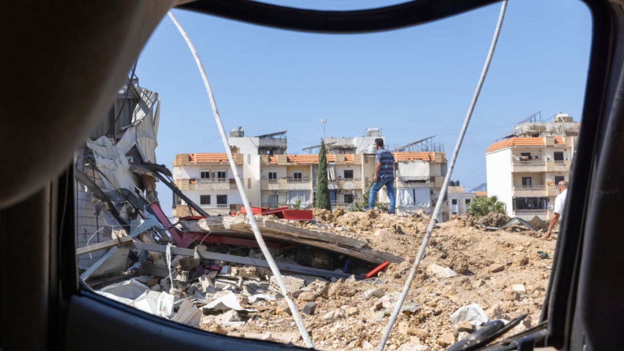 JIYEH, LEBANON - SEPTEMBER 25: A man seen through a destroyed police vehicle examines the destruction after an early morning Israeli airstrike hit a vehicle mechanic shop on September 25, 2024 in Jiyeh, Lebanon. Lebanese authorities have reported more than 500 people have been killed in Israeli airstrikes in Lebanon since Monday, as residents in affected areas along Lebanon's southern border with Israel flock north to the capital, Beirut. (Photo by Daniel Carde/Getty Images)