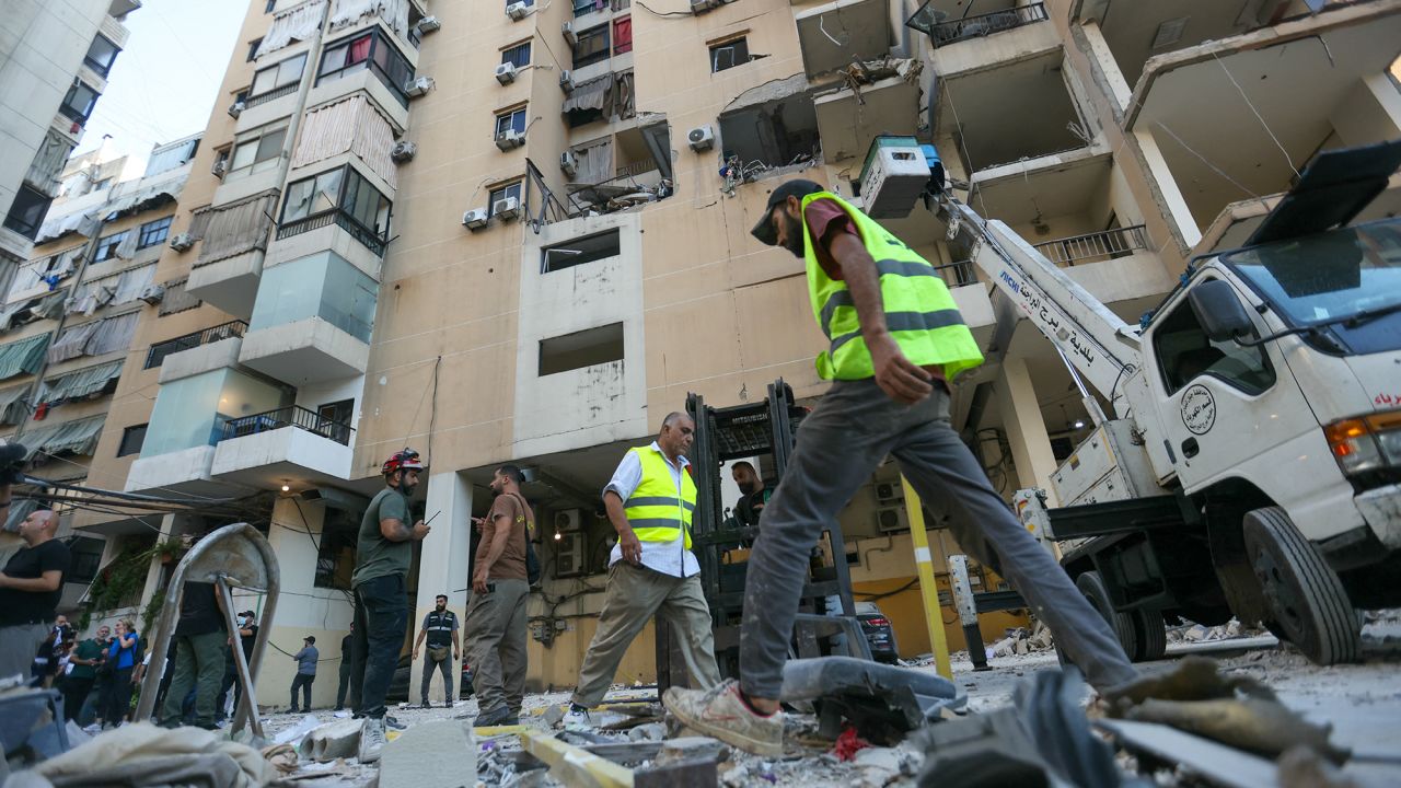 People and rescuers gather at the site of an Israeli airstrike that targeted an apartment in Beirut's southern suburbs on September 26.