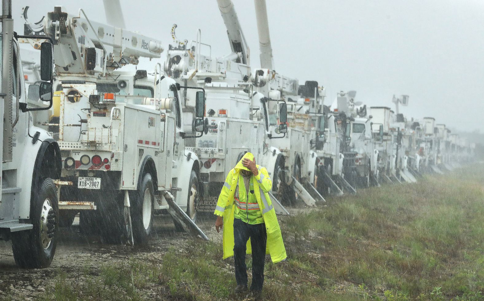 Charles Starling, a lineman with Team Fishel, walks by a row of electrical line trucks staged in a field in The Villages, Florida, on Thursday.