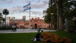 TOPSHOT - A homeless man sleeps at Plaza de Mayo square in front of Casa Rosada presidential palace in Buenos Aires on September 25, 2024. Poverty in Argentina reached 52,9 percent of the population in the first six months of Javier Milei's government, reflecting the impact of the 50 percent devaluation carried out in December and a fiscal adjustment policy that, focused on reducing spending and inflation, deepened the economic recession. (Photo by LUIS ROBAYO / AFP) (Photo by LUIS ROBAYO/AFP via Getty Images)