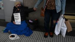 Unemployed Viviana Quevedo, 57, is greeted by a woman as she sits on a street holding a sign that reads "I am looking for a job in order to be able to rent" in Buenos Aires on September 25, 2024. Poverty in Argentina reached 52,9 percent of the population in the first six months of Javier Milei's government, reflecting the impact of the 50 percent devaluation carried out in December and a fiscal adjustment policy that, focused on reducing spending and inflation, deepened the economic recession. (Photo by LUIS ROBAYO / AFP) (Photo by LUIS ROBAYO/AFP via Getty Images)