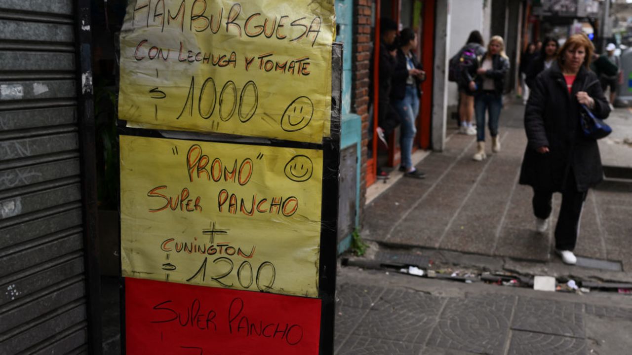 A woman walks past signs with food prices in Avellaneda, Buenos Aires province, on September 25, 2024. Poverty in Argentina reached 52,9 percent of the population in the first six months of Javier Milei's government, reflecting the impact of the 50 percent devaluation carried out in December and a fiscal adjustment policy that, focused on reducing spending and inflation, deepened the economic recession. (Photo by LUIS ROBAYO / AFP) (Photo by LUIS ROBAYO/AFP via Getty Images)