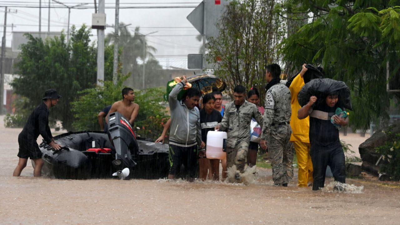 National guard members and police officers help people on a flooded street after the hit of Hurricane John in Acapulco, Mexico, on September 26, 2024. Hurricane John, which made landfall in Mexico on September 23, leaving at least five dead, re-formed as a cyclone early September 26, and is expected to hit the country again, authorities said. (Photo by Francisco Robles / AFP) (Photo by FRANCISCO ROBLES/AFP via Getty Images)