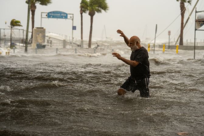 Một người đàn ông băng qua khu vực ngập lụt trên bờ biển Gulfport, Florida, vào thứ năm.