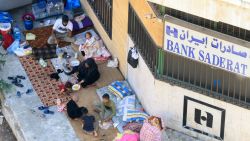 EDITORS NOTE: Graphic content / A displaced family fleeing violence in southern Lebanon take shelter at the entrance of a branch of Iran's Saderat Bank in Sidon, on September 27, 2024. Israel and Hezbollah traded fire on September 27 after the United States and its allies failed to secure a halt in clashes that have killed more than 700 people in Lebanon this week. (Photo by Mahmoud ZAYYAT / AFP) (Photo by MAHMOUD ZAYYAT/AFP via Getty Images)