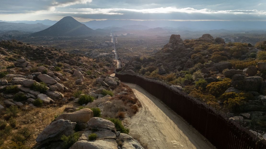 The US-Mexico border fence stretches through rough terrain on September 20, 2024, near Jacumba Hot Springs, California.