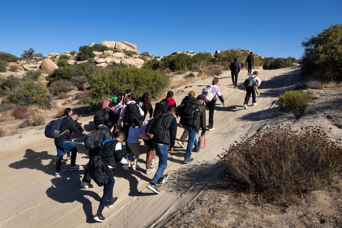 Colombian asylum seekers walk along a desert road after crossing the US-Mexico on September 22, 2024 near Jacumba Hot Springs, California.