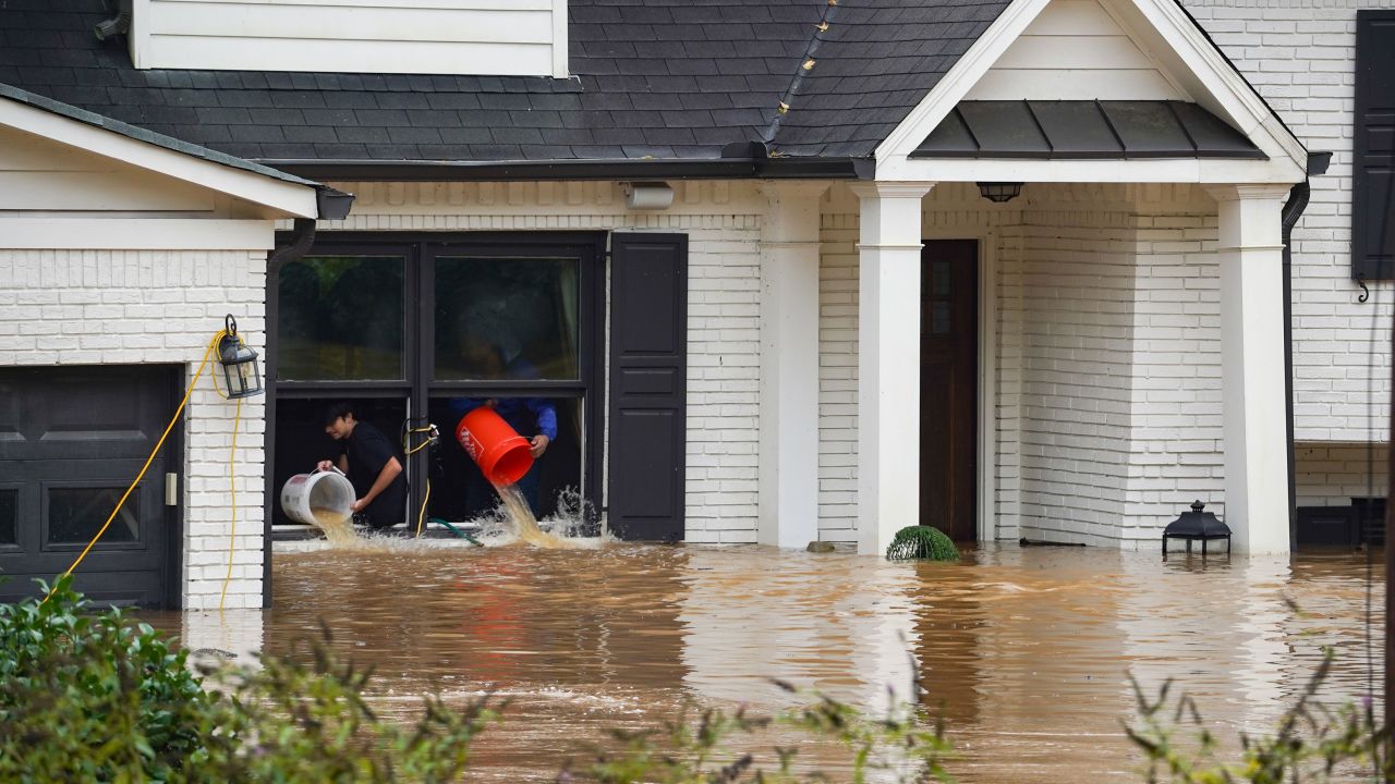 People use buckets to remove water from a home near Peachtree Creek in Atlanta on Friday, September 27, after Hurricane Helene brought heavy rain overnight.