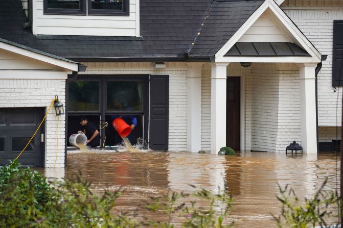 People use buckets to remove water from a home near Peachtree Creek in Atlanta on Friday after Hurricane Helene brought heavy rain overnight.