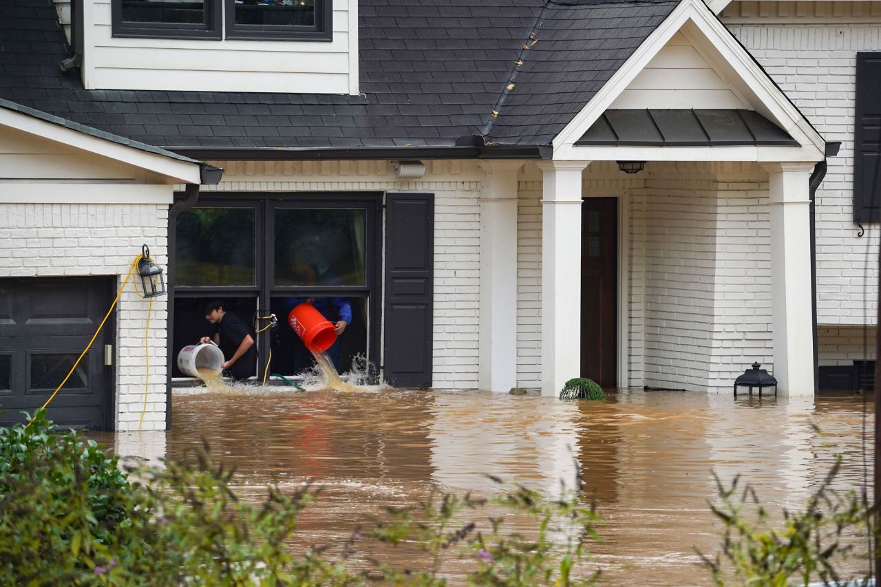 People use buckets to remove water from a home near Peachtree Creek in Atlanta on Friday, September 27, after Hurricane Helene brought heavy rain overnight.