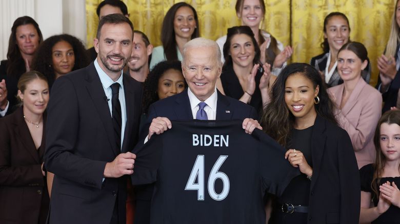 WASHINGTON, DC - SEPTEMBER 23: U.S. President Joe Biden is presented a jersey from NJ/NY Gotham FC head coach Juan Carlos Amorós and forward Midge Purce during a ceremony honoring their 2023 National Women's Soccer League (NWSL) championship in the East Room at the White House on September 23, 2024 in Washington, DC. NJ/NY Gotham FC defeated the OL Reign (now Seattle Reign FC), 2-1 to win the 2023 NWSL Championship.  (Photo by Kevin Dietsch/Getty Images)