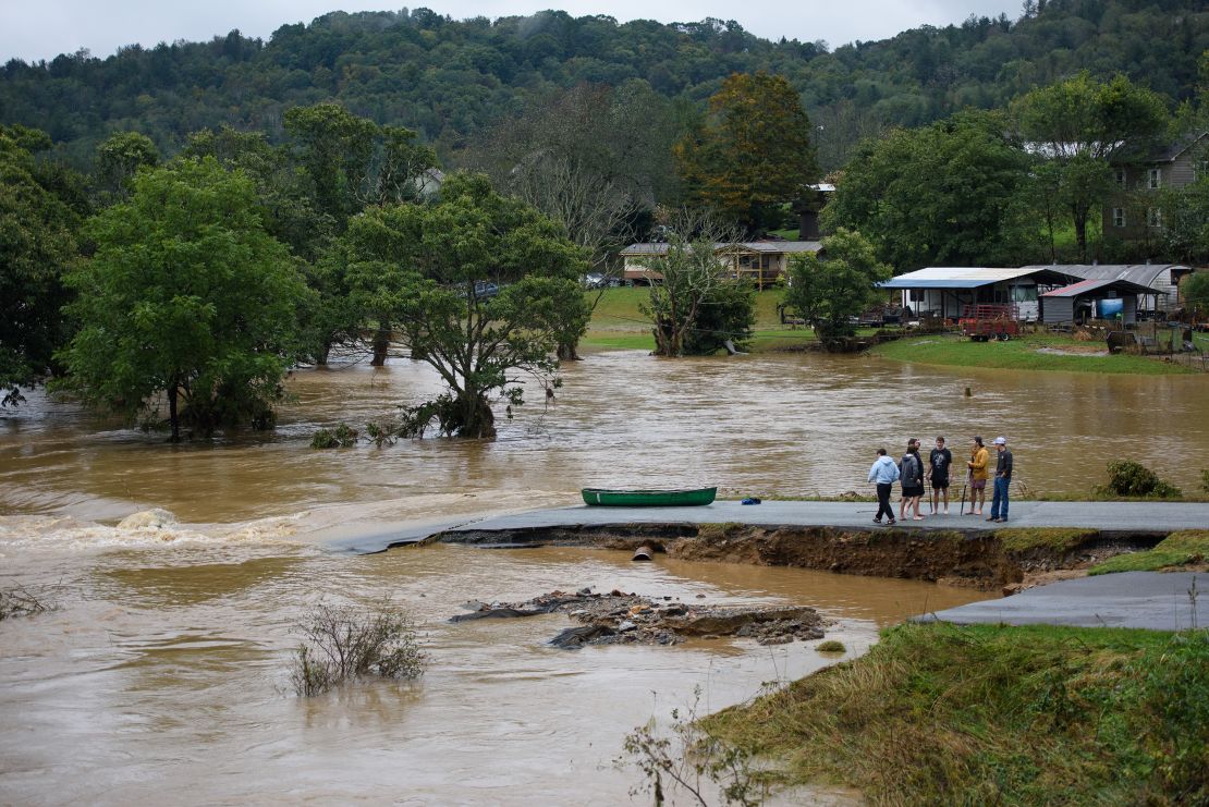 Residents talk after having canoed the flooded South Fork New River for 32 minutes and landing at a washed out road on September 27, 2024 in Boone, North Carolina.