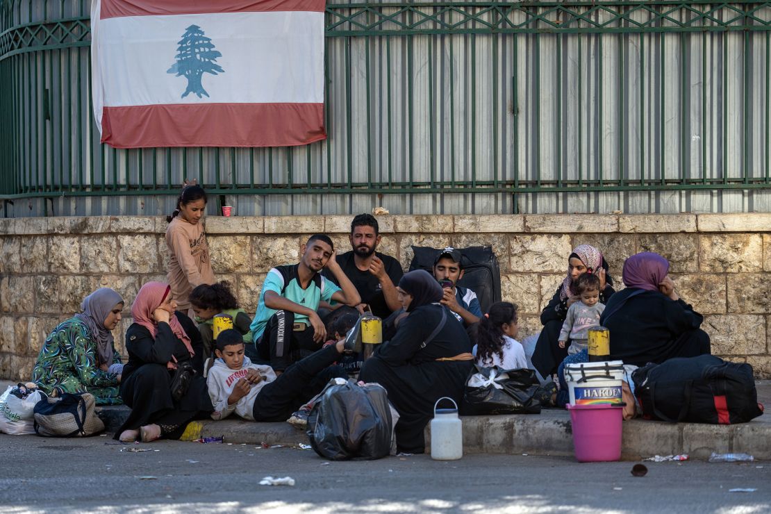 Internally-displaced people sit beneath a Lebanese flag in the Dahieh neighbourhood on September 28, 2024 in Beirut, Lebanon.