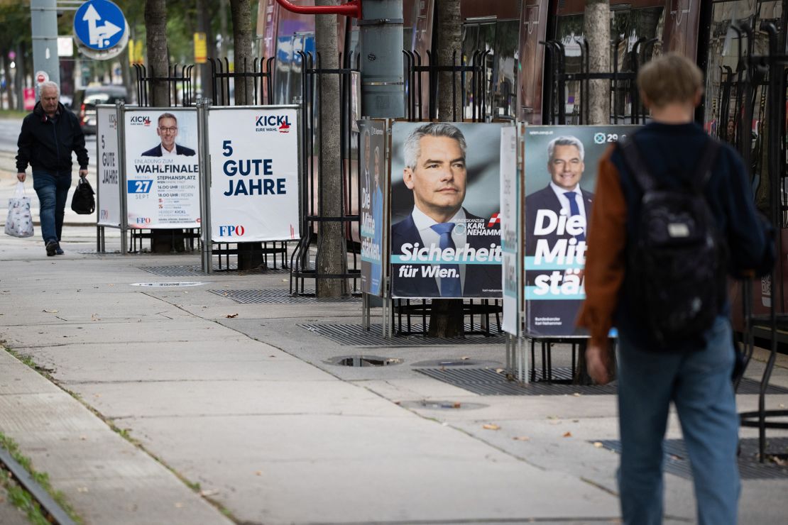 People walk past election campaign billboards showing Austrian Chancellor Karl Nehammer and the FPÖ's Herbet Kickl in Vienna.