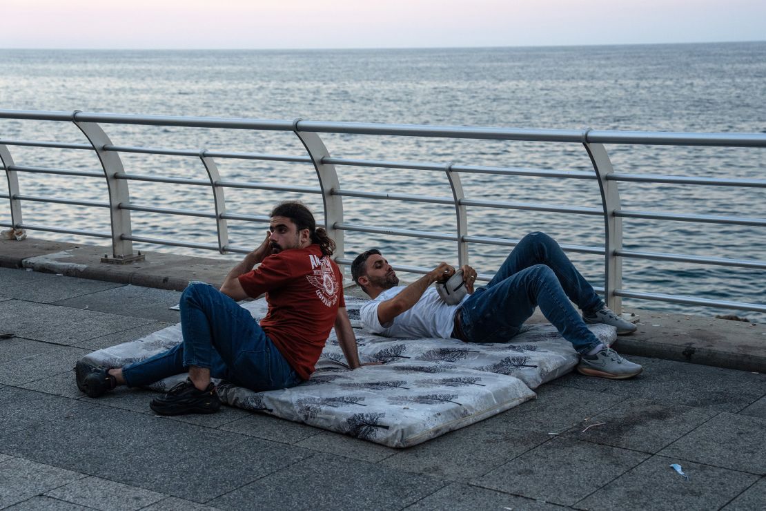 men rest on mattresses near the sea in beirut, lebanon, after being displaced by israeli airstrikes on september 28, 2024.