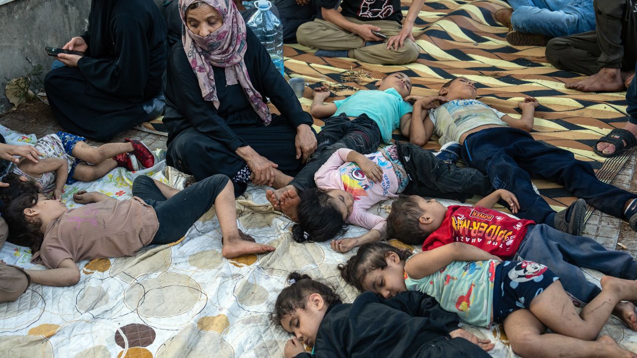 A woman watches over sleeping children as they shelter outside after being displaced by Israeli airstrikes on September 28, 2024 in Beirut, Lebanon.