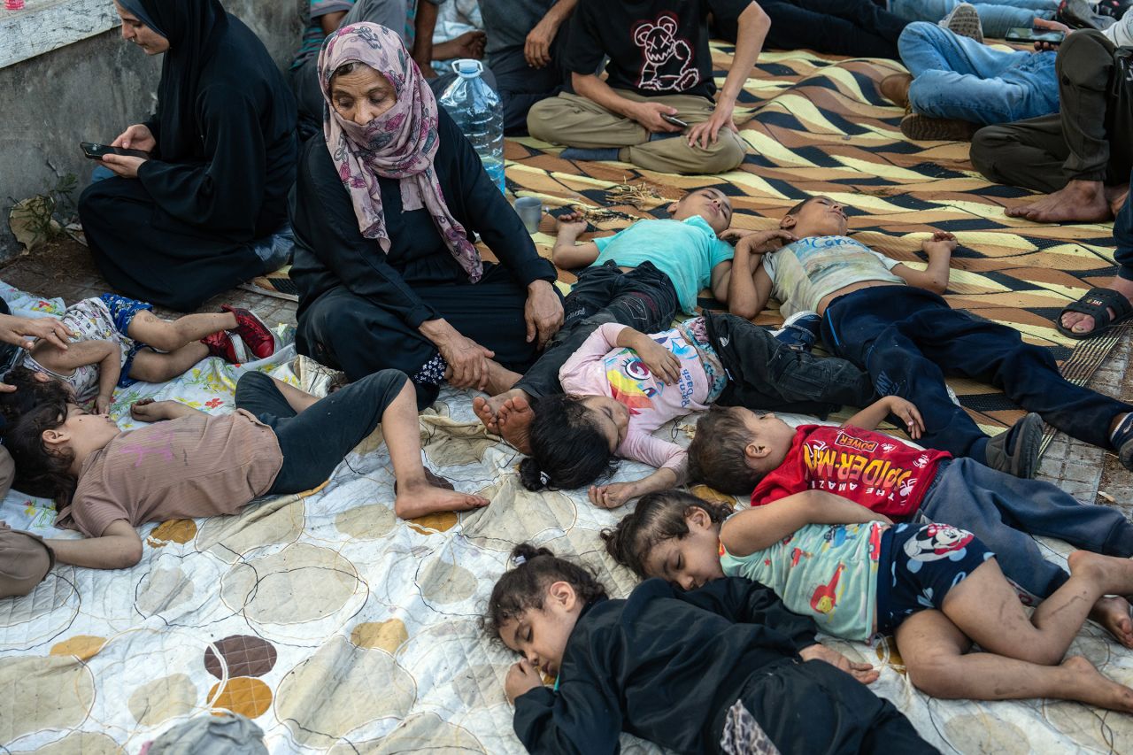 A woman watches over sleeping children as they shelter outside after being displaced by Israeli airstrikes on September 28, 2024 in Beirut, Lebanon.