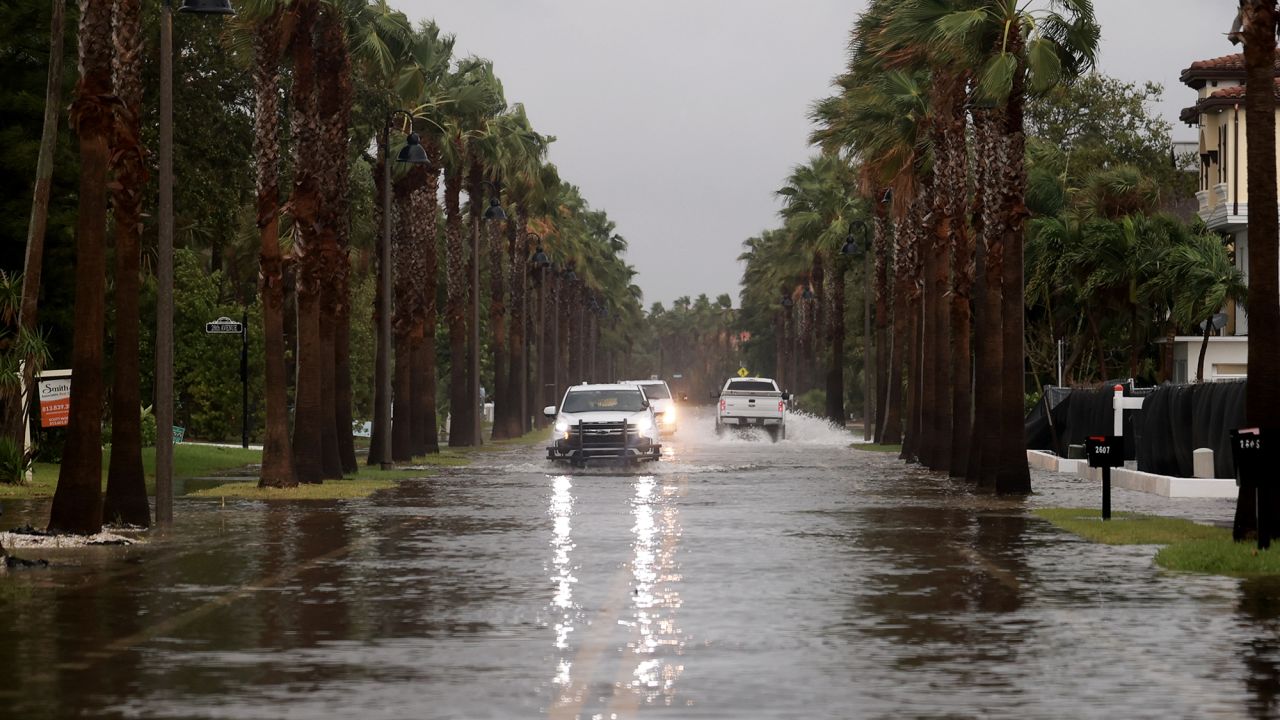 Vehicles drive along a flooded street as Hurricane Helene churns offshore on September 26, in St. Pete Beach, Florida.