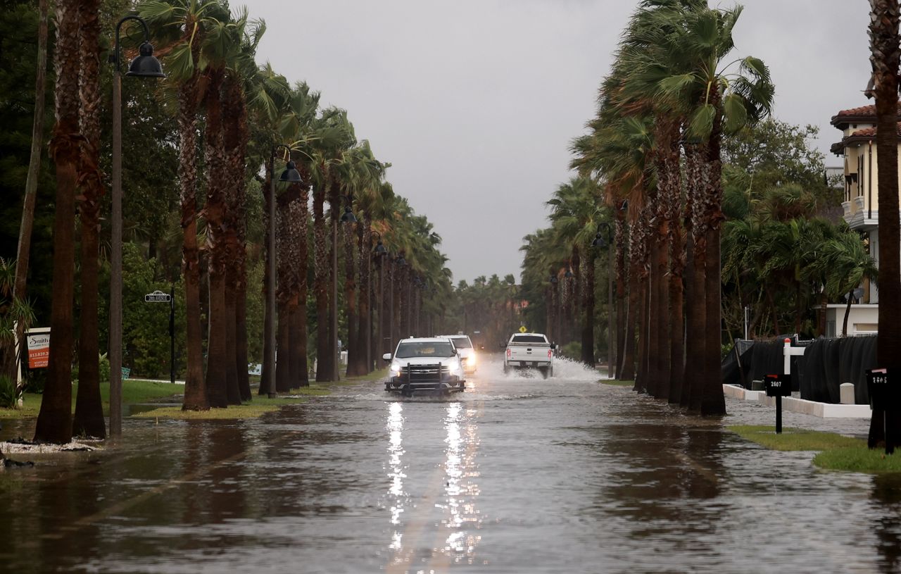 Vehicles drive along a flooded street as Hurricane Helene churns offshore on September 26, in St. Pete Beach, Florida.