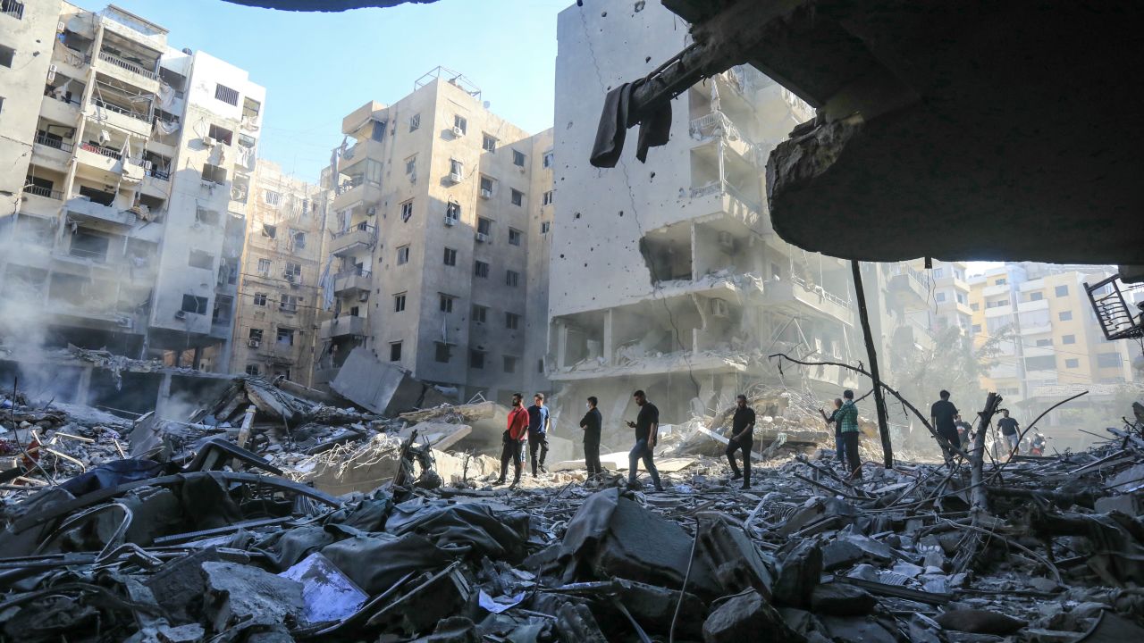 TOPSHOT - People walk amid the rubble of buildings which were levelled on September 27 by Israeli strikes that targeted and killed Hezbollah leader Hassan Nasrallah in the Haret Hreik neighbourhood of Beirut's southern suburbs, on September 29, 2024. Israel killed Hezbollah chief Hassan Nasrallah in a huge air strike in Lebanon, dealing the movement a seismic blow that Prime Minister Benjamin Netanyahu on September 28 called a "turning point" for his country. (Photo by AFP) (Photo by -/AFP via Getty Images)