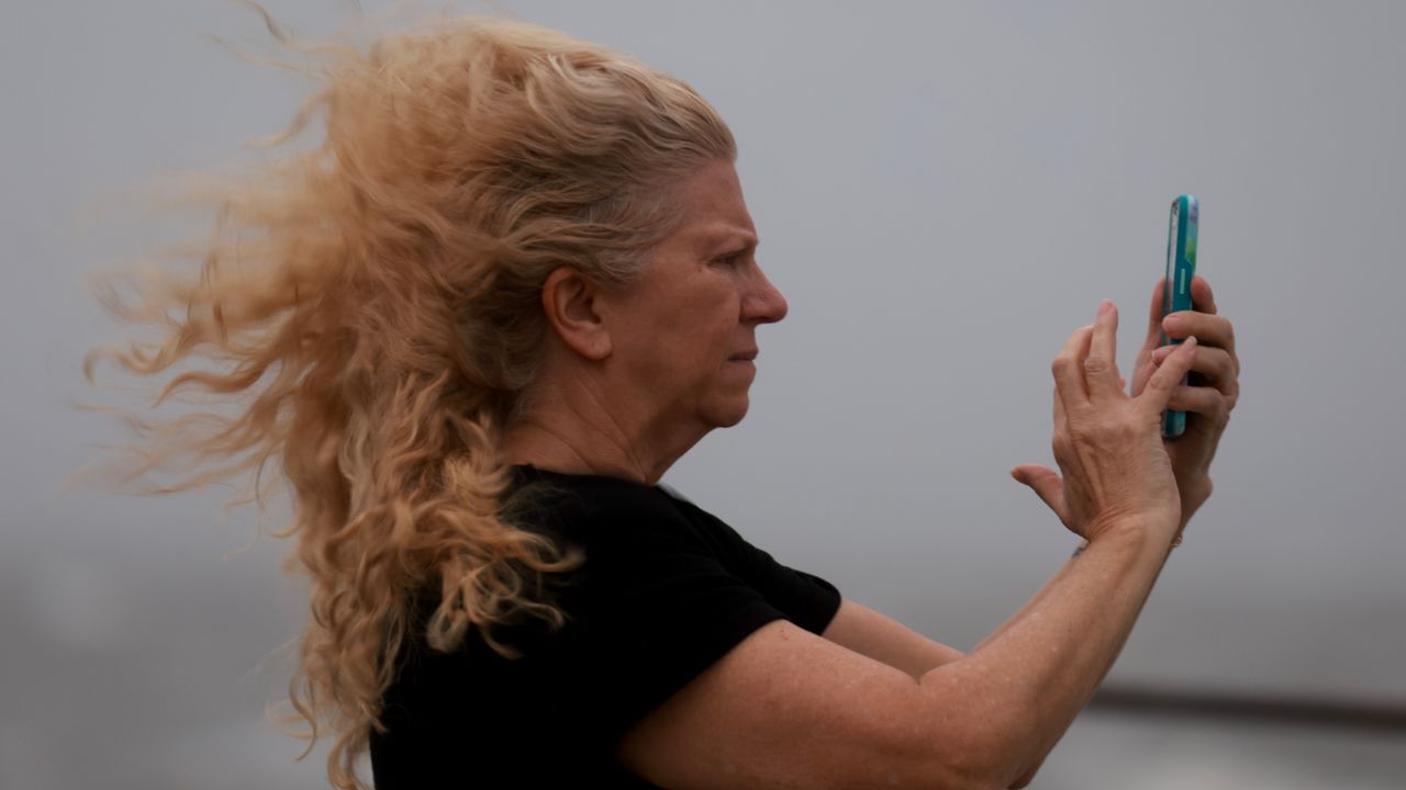 Carol Poulson uses her phone to document the impacts of Hurricane Helene offshore in St. Petersburg, Florida, on September 26.