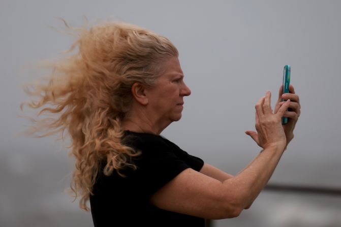 Carol Poulson uses her phone to document the impacts of Hurricane Helene as it builds offshore in St. Petersburg, Florida on Thursday.