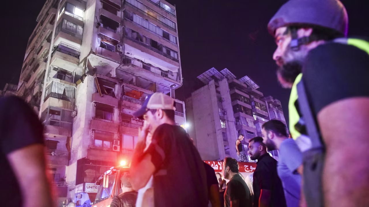 People gather outside an apartment building hit by an airstrike in Beirut on Monday.
