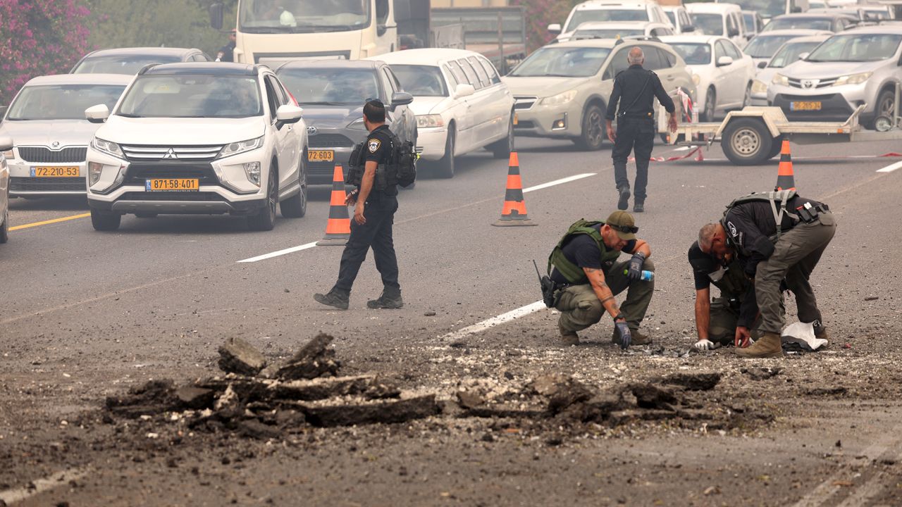 Members of Israeli security forces inspect the impact site of a reported rocket fired from Lebanon, on the Horeshim interchange in central Israel, on October 1.