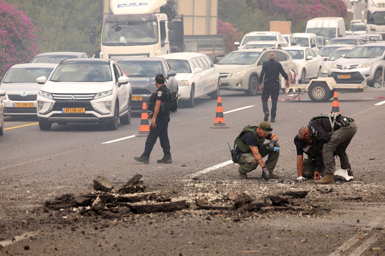 Members of Israeli security forces inspect the impact site of a reported rocket fired from Lebanon, on the Horeshim interchange in central Israel, on October 1.