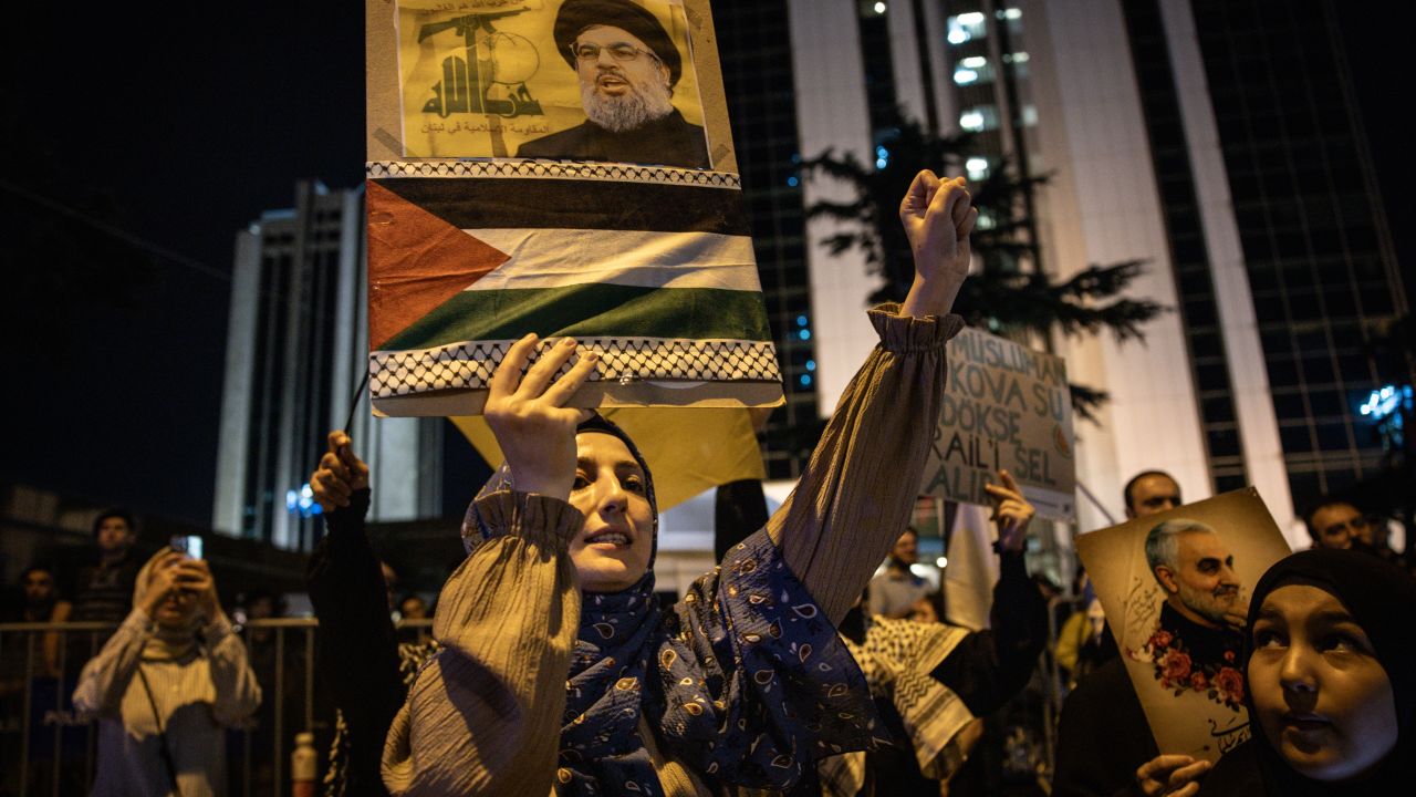 ISTANBUL, TURKEY - SEPTEMBER 28: A woman holds a poster of Hezbollah leader Sayyed Hassan Nasrallah in front of the Israeli Consulate during a solidarity march and protest for Palestine and Lebanon outside the Israeli Consulate on September 28, 2024 in Istanbul, Turkey. The protests come as the world reacts to the announcement by Israel that it had killed Hezbollah leader Sayyed Hassan Nasrallah in an airstrike yesterday.  (Photo by Chris McGrath/Getty Images)