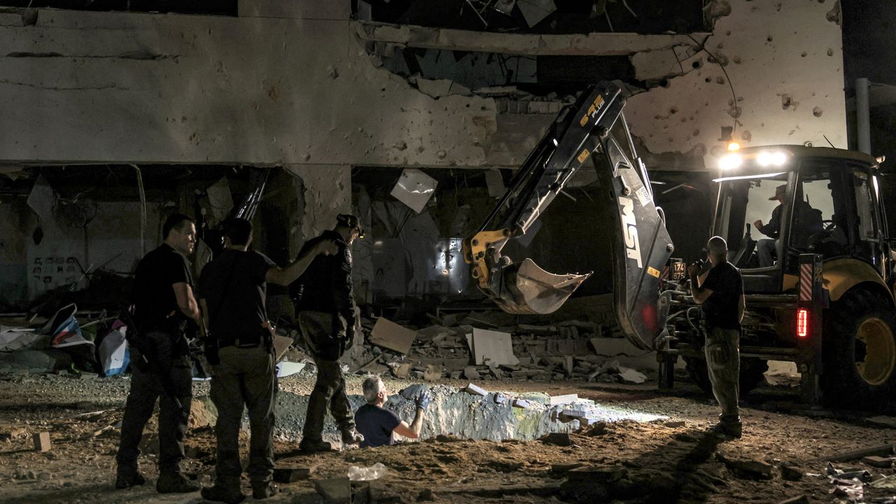 An excavator works by a crater left by an exploded projectile at a heavily-damaged school building in Israel's southern city of Gedera on October 1.