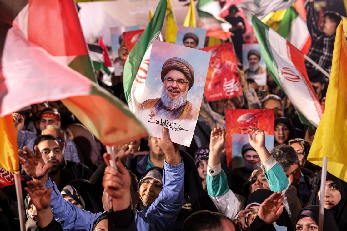 A protester holds a sign with the face of slain Hezbollah leader Hassan Nasrallah during a celebratory rally after Iran fired rocket fire at Israel in Palestine Square in Tehran on October 1, 2024.