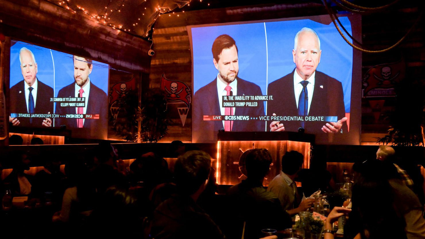 Sen. JD Vance and Gov. Tim Walz are shown on screen during a vice presidential debate watch party in New York on Oct. 1, 2024.